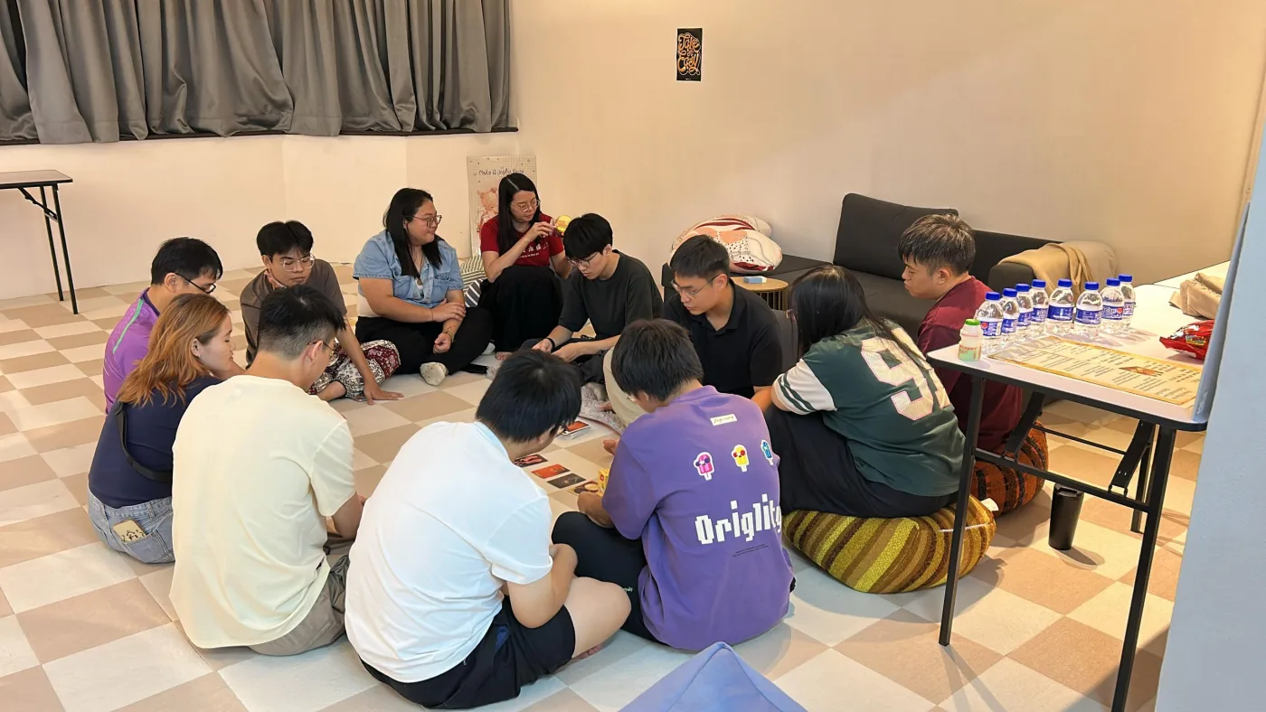 青年学员围坐地上一同玩桌游,法师与义工在旁参与