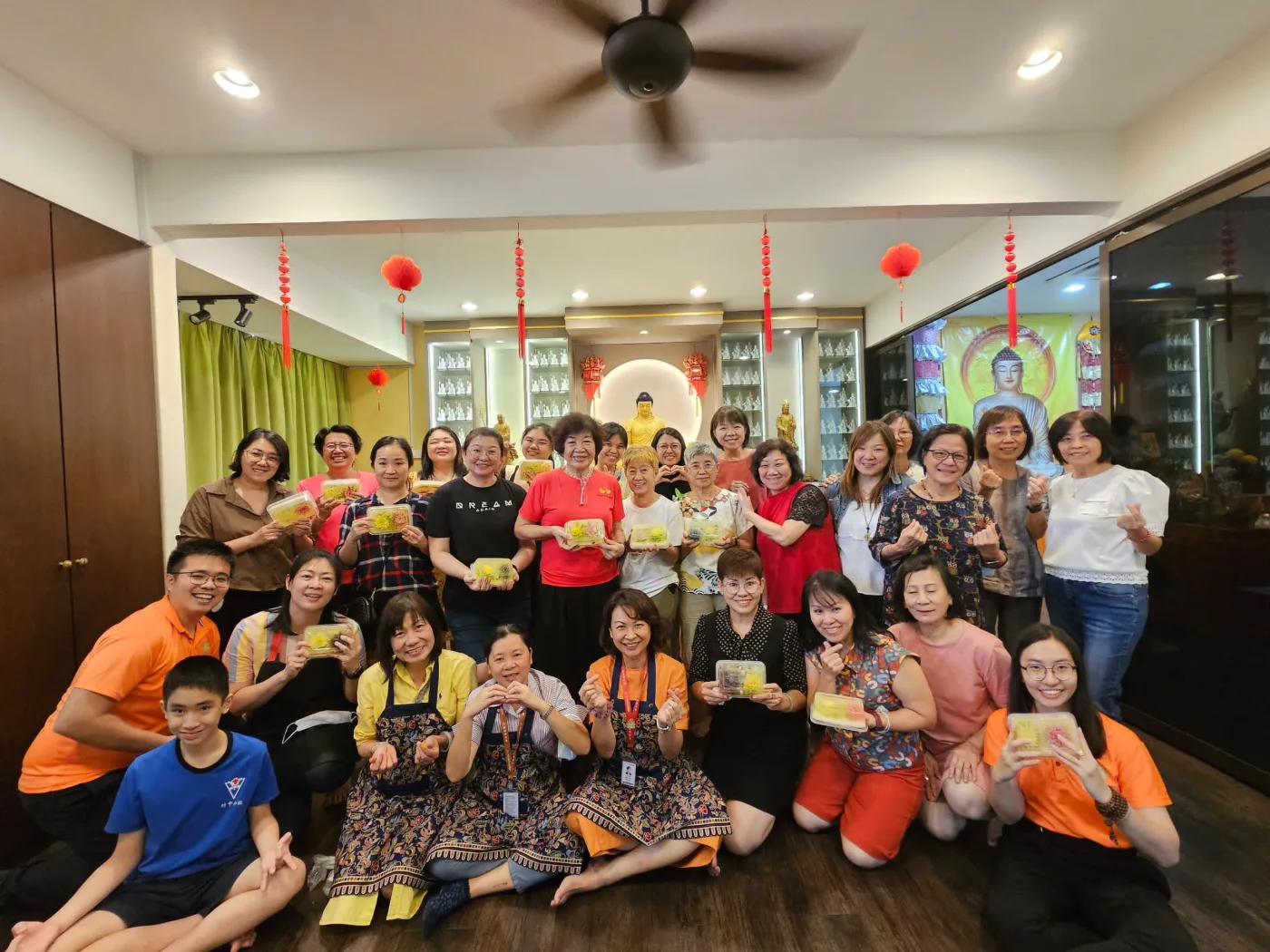 美食工作坊学员手捧亲手制作的糕点,在佛堂前大合照