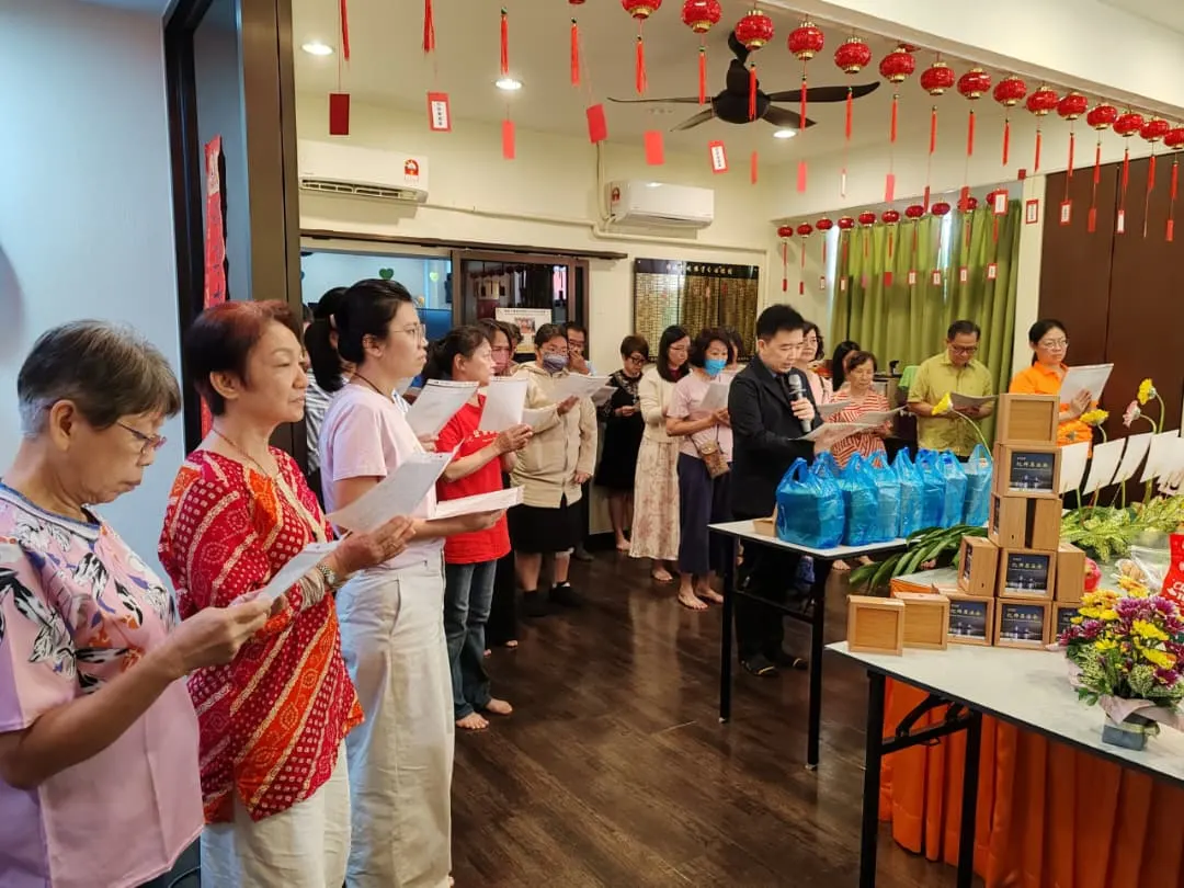 信众手持经本列队诵经,一旁备有供品与结缘物资