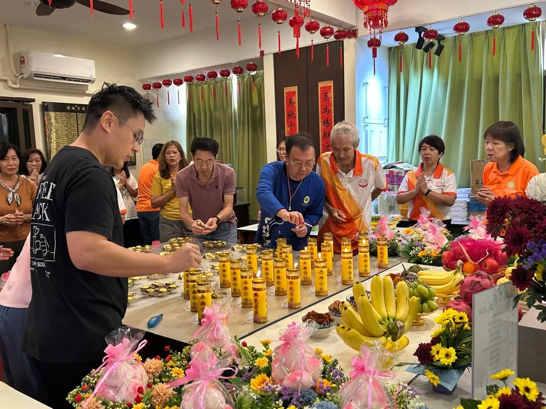 信众在药师佛诞法会点燃供灯,供桌上摆满鲜花与水果供品